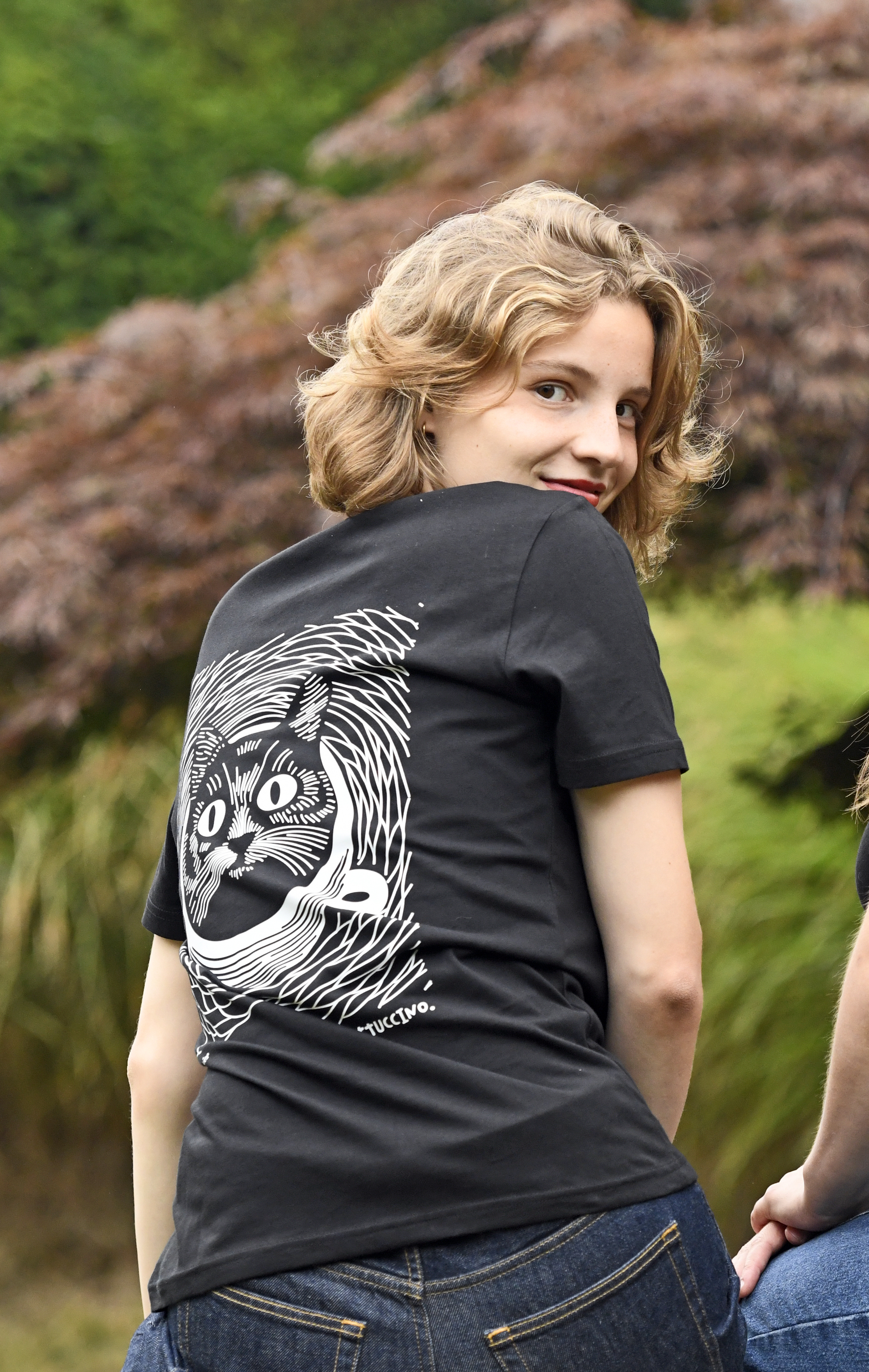 Vrouwelijk model draagt het zwarte 'Cattuccino' T-shirt. T-shirt in biokatoen met kat en koffie.